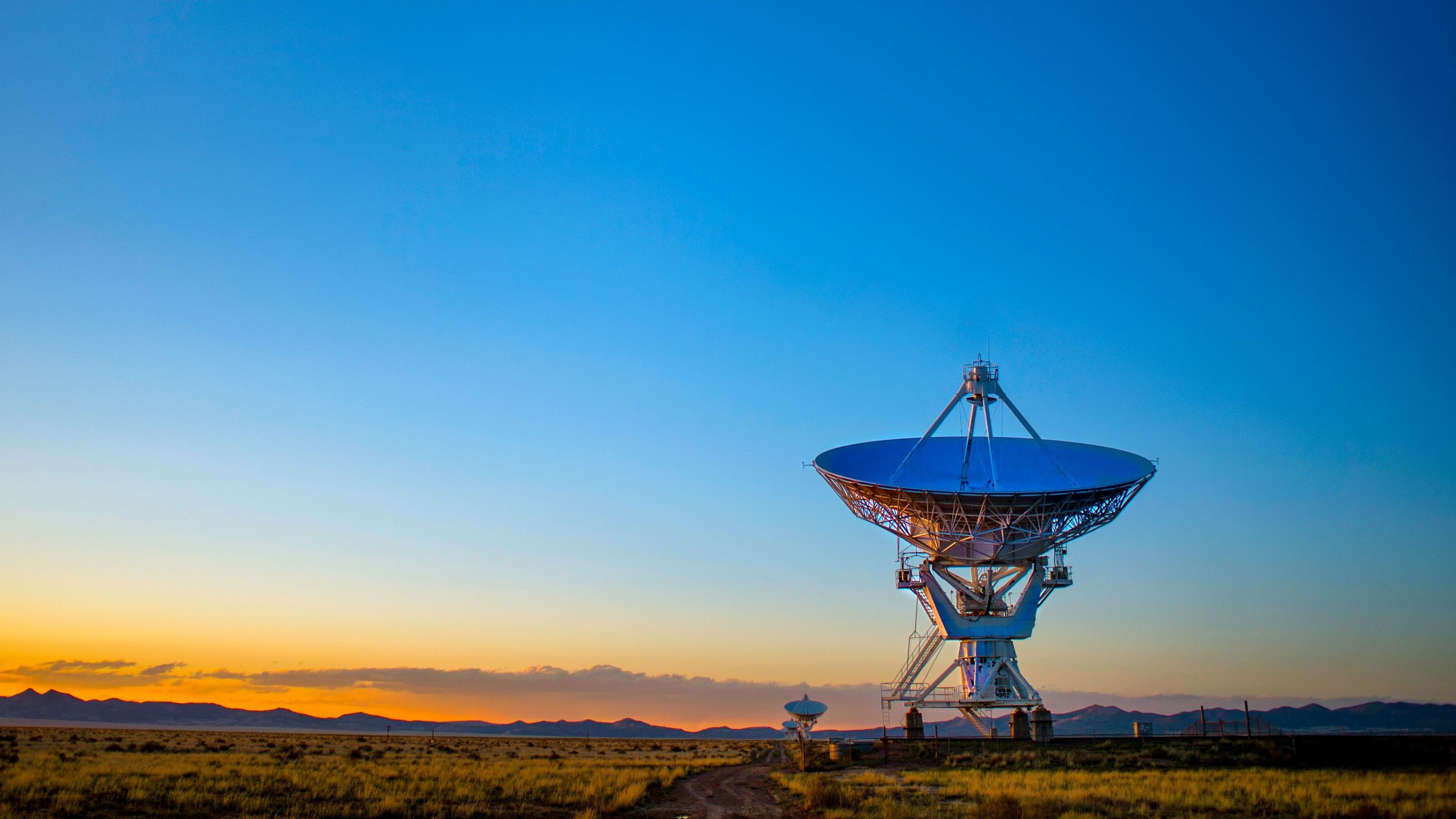 Eine riesige Satellitenschüssel in der Dämmerung in der Wüste